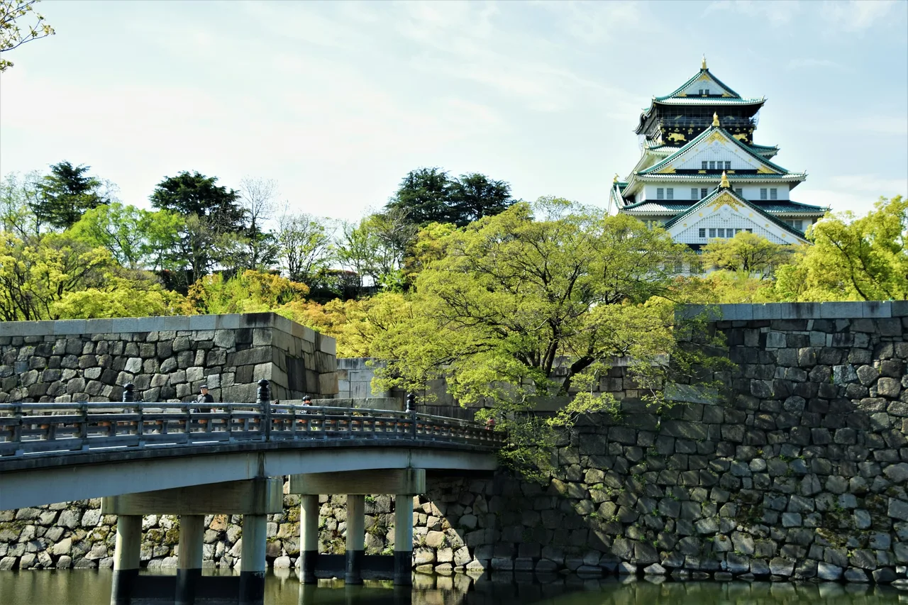 Osaka Castle above a stone bridge, surrounded by fresh green trees